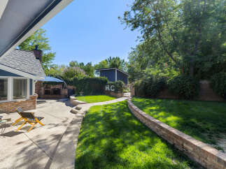 Enjoy outdoor living in this spacious backyard featuring a charming brick patio and a lush green lawn perfect for recreation.