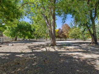 Discover this expansive property featuring mature trees and a charming white fence, perfect for creating your dream home or equestrian estate.