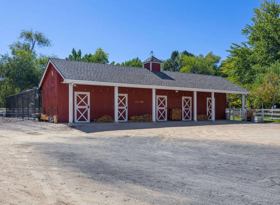 This charming red barn offers ample space with multiple stalls, perfect for equestrian enthusiasts or as a versatile workshop.