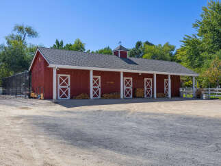 This charming red barn offers ample space with multiple stalls, perfect for equestrian enthusiasts or as a versatile workshop.
