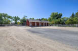 Discover this charming equestrian property featuring a classic red barn with multiple stalls and white cross-buck doors.