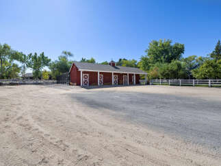 Discover this charming equestrian property featuring a classic red barn with multiple stalls and white cross-buck doors.