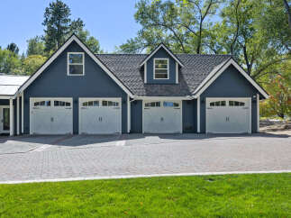 This stunning property features a spacious 4-car garage with elegant white doors and charming architectural details.