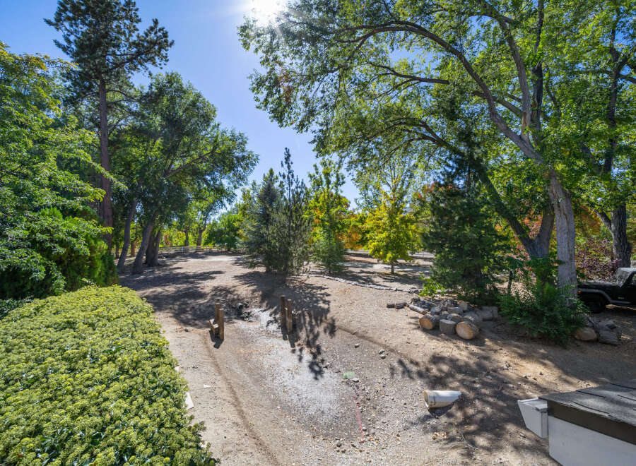 Discover this charming property featuring a lush, manicured hedge in the foreground, leading to a serene, tree-lined yard.