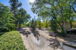 Discover this charming property featuring a lush, manicured hedge in the foreground, leading to a serene, tree-lined yard.