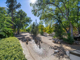 Discover this charming property featuring a lush, manicured hedge in the foreground, leading to a serene, tree-lined yard.