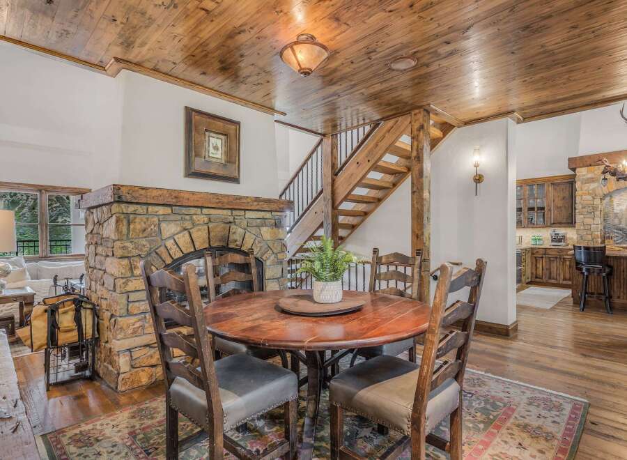 Experience rustic charm in this inviting dining area, featuring a grand stone fireplace and a warm wooden ceiling.