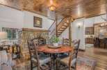 Experience rustic charm in this inviting dining area, featuring a grand stone fireplace and a warm wooden ceiling.