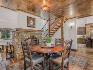 Experience rustic charm in this inviting dining area, featuring a grand stone fireplace and a warm wooden ceiling.