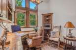 Discover a rustic home office featuring a large wooden desk with a computer, complemented by a comfortable leather executive chair and a unique animal hide accent.