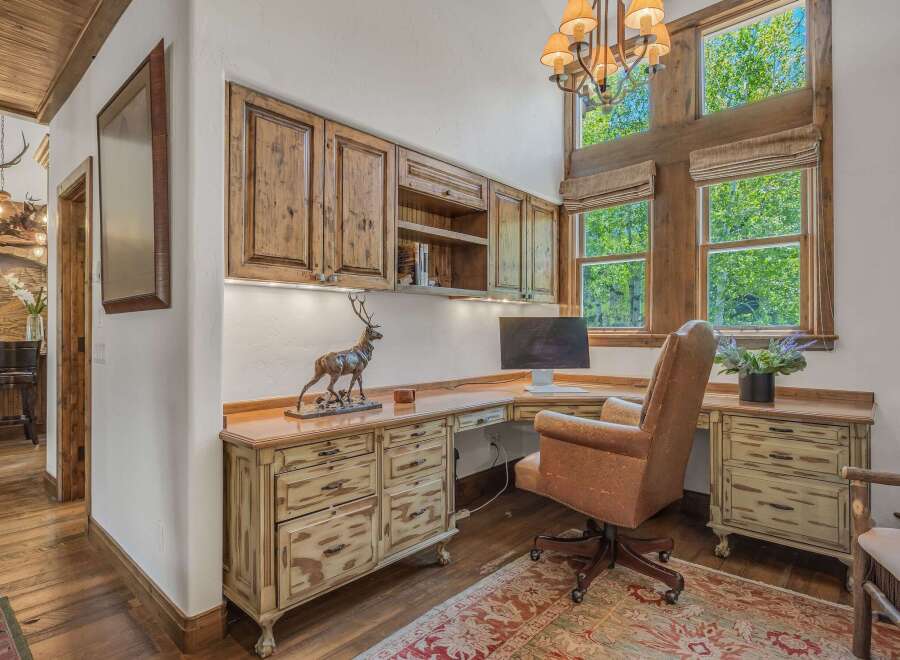 This rustic home office features custom wood cabinetry and a large desk, perfect for a productive workspace.