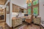 This rustic home office features custom wood cabinetry and a large desk, perfect for a productive workspace.