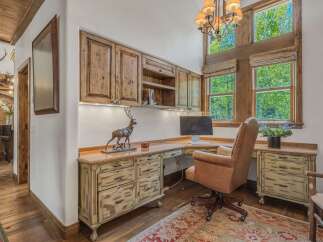 This rustic home office features custom wood cabinetry and a large desk, perfect for a productive workspace.