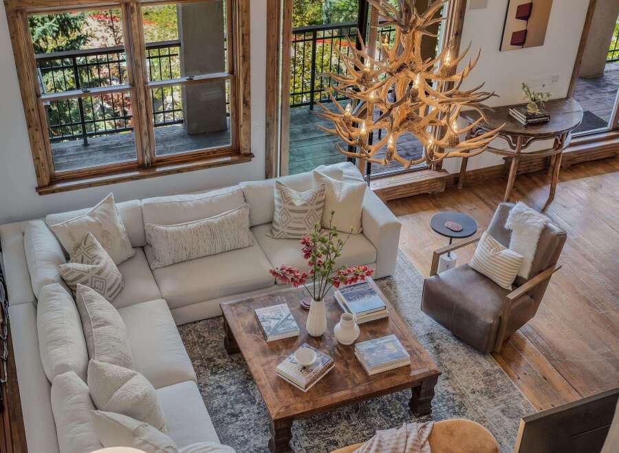 Experience rustic luxury in this stunning living room, featuring a plush sectional sofa and a unique antler chandelier that adds a touch of natural elegance.
