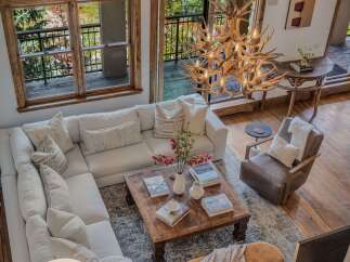 Experience rustic luxury in this stunning living room, featuring a plush sectional sofa and a unique antler chandelier that adds a touch of natural elegance.