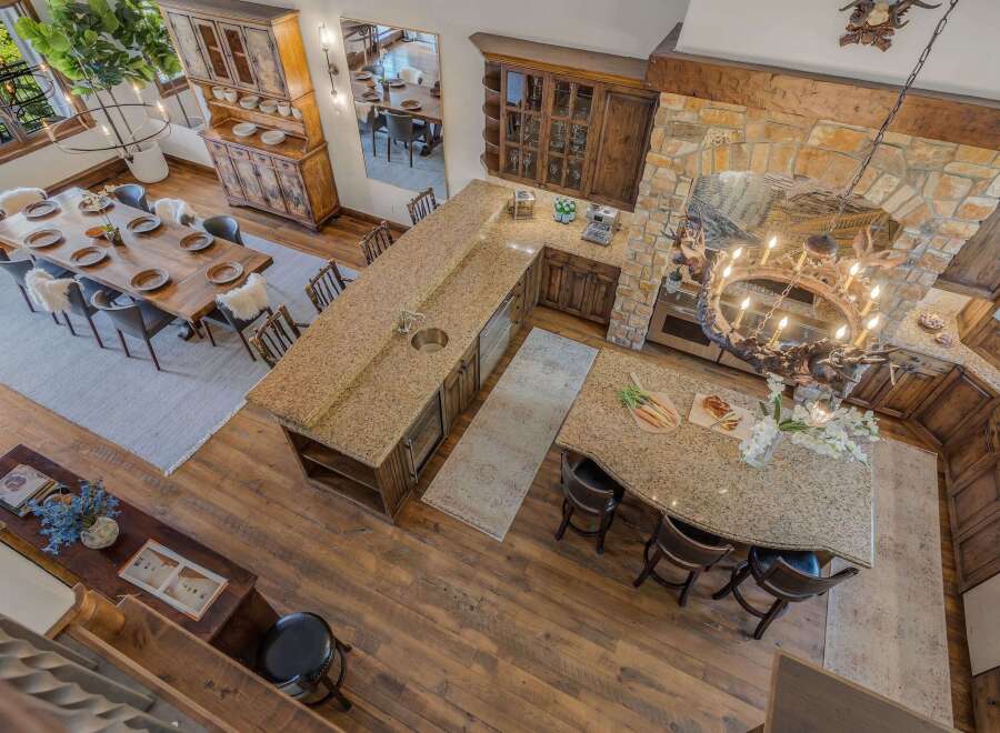 Experience rustic elegance in this spacious open-concept living area, featuring a large wooden dining table perfect for gatherings and a stunning granite-topped kitchen island with ample seating.