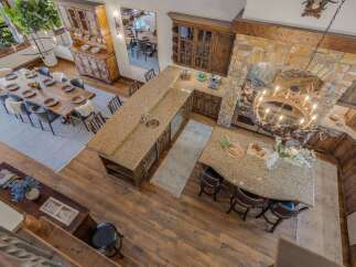 Experience rustic elegance in this spacious open-concept living area, featuring a large wooden dining table perfect for gatherings and a stunning granite-topped kitchen island with ample seating.