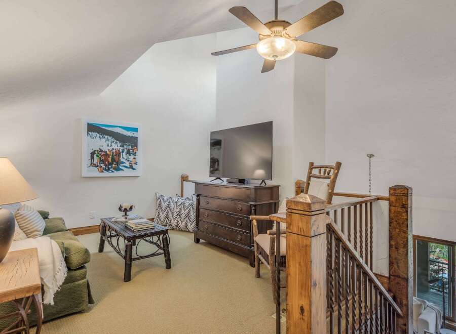 Experience cozy living in this charming loft featuring a comfortable green sofa, a rustic coffee table, and a large flat-screen TV perfect for entertainment.