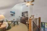 Experience cozy living in this charming loft featuring a comfortable green sofa, a rustic coffee table, and a large flat-screen TV perfect for entertainment.