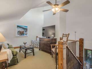 Experience cozy living in this charming loft featuring a comfortable green sofa, a rustic coffee table, and a large flat-screen TV perfect for entertainment.