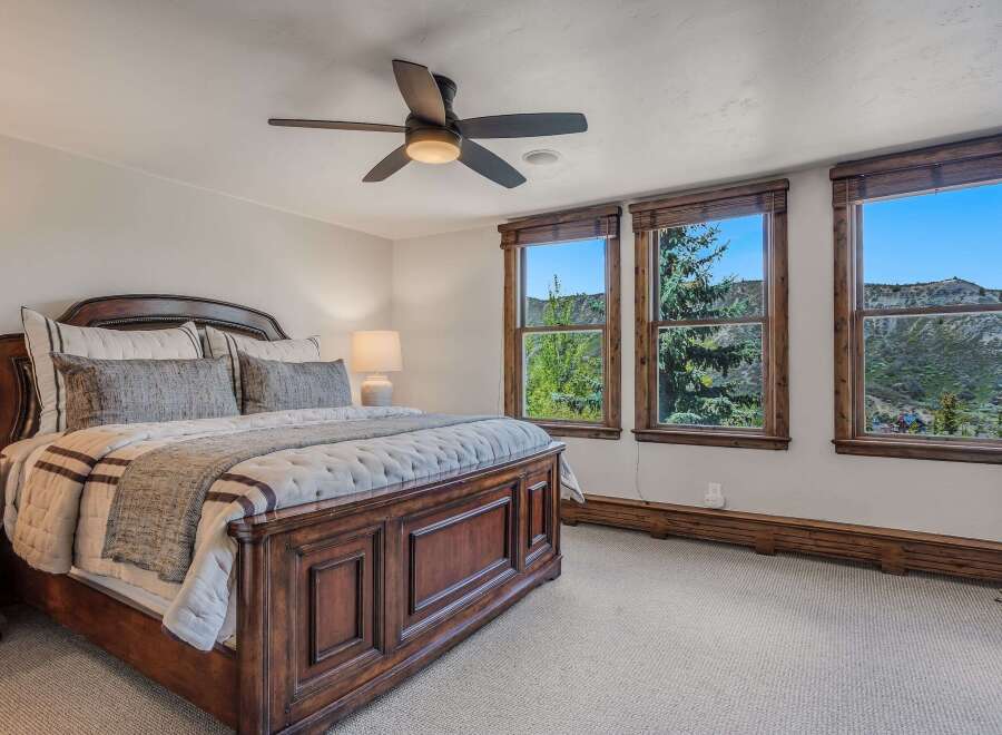 Experience breathtaking mountain views from this stunning bedroom, featuring a luxurious wooden bed frame and plush bedding.