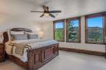 Experience breathtaking mountain views from this stunning bedroom, featuring a luxurious wooden bed frame and plush bedding.
