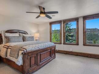 Experience breathtaking mountain views from this stunning bedroom, featuring a luxurious wooden bed frame and plush bedding.