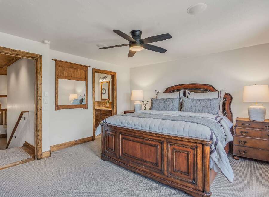 Experience rustic elegance in this master bedroom featuring a grand wooden bed and a luxurious upholstered headboard.