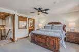 Experience rustic elegance in this master bedroom featuring a grand wooden bed and a luxurious upholstered headboard.