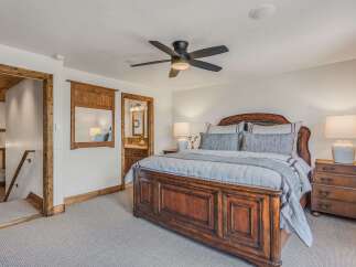 Experience rustic elegance in this master bedroom featuring a grand wooden bed and a luxurious upholstered headboard.