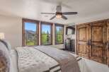 Experience breathtaking mountain views from this luxurious bedroom, featuring three large windows that frame the stunning landscape.