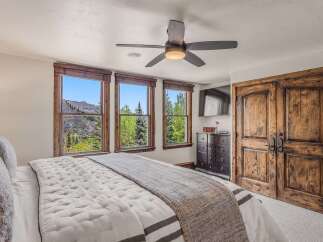 Experience breathtaking mountain views from this luxurious bedroom, featuring three large windows that frame the stunning landscape.
