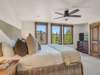 Experience luxurious mountain living in this stunning bedroom, featuring a plush king-size bed adorned with decorative pillows and a cozy quilted throw.
