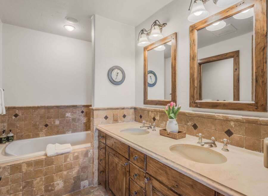 This luxurious bathroom features a deep soaking tub and a spacious double vanity with rustic wooden cabinetry.
