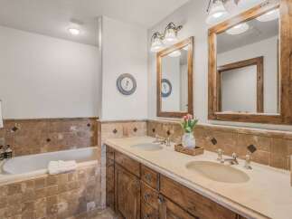 This luxurious bathroom features a deep soaking tub and a spacious double vanity with rustic wooden cabinetry.