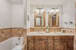 Experience luxury in this stunning bathroom featuring a deep soaking tub and a spacious double vanity with rustic wooden cabinetry.
