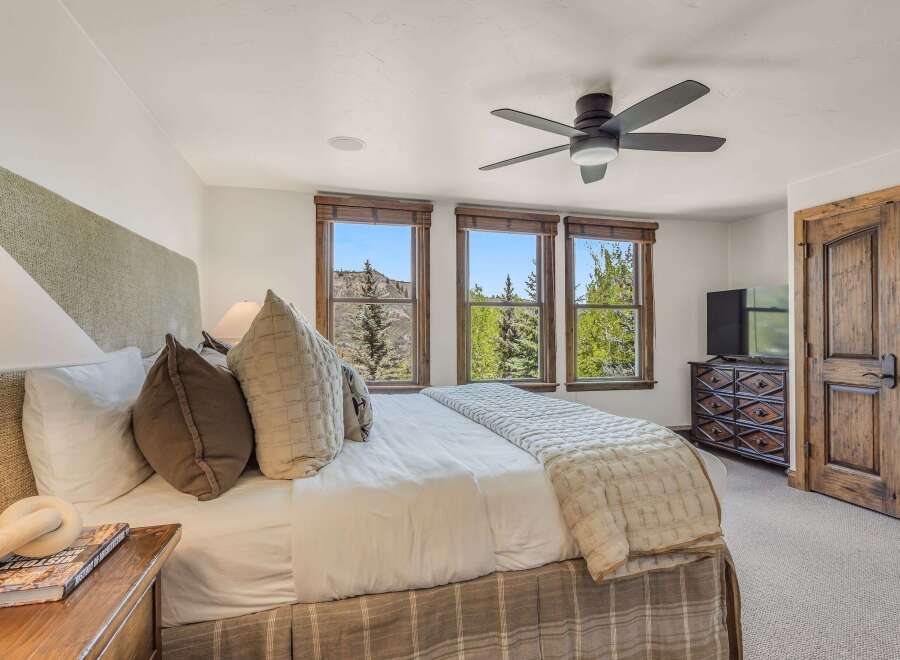 Experience luxurious mountain living in this stunning bedroom, featuring a plush king-size bed adorned with decorative pillows and a cozy quilted throw.