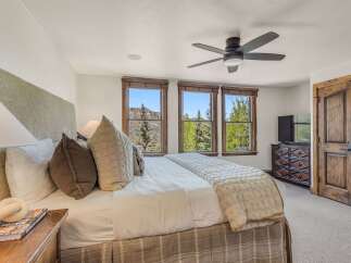 Experience luxurious mountain living in this stunning bedroom, featuring a plush king-size bed adorned with decorative pillows and a cozy quilted throw.