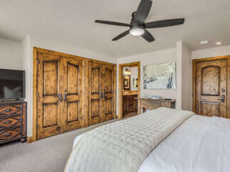 Experience rustic elegance in this master bedroom, featuring a luxurious king-sized bed adorned with a textured quilt.
