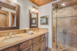 This luxurious bathroom features a spacious double vanity with a granite countertop and wooden cabinetry, complemented by elegant fixtures.