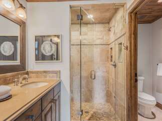 Experience luxury in this stunning bathroom featuring a spacious walk-in shower with elegant stone tile and a glass enclosure.
