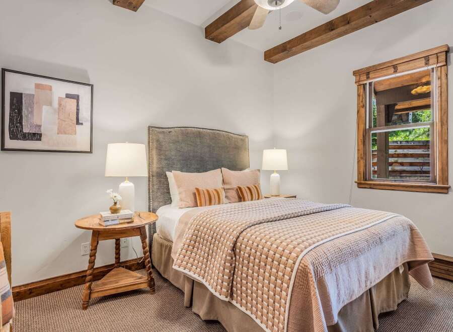 Experience rustic charm in this cozy bedroom, featuring exposed wooden beams and a plush upholstered headboard.