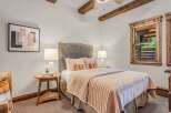 Experience rustic charm in this cozy bedroom, featuring exposed wooden beams and a plush upholstered headboard.