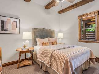 Experience rustic charm in this cozy bedroom, featuring exposed wooden beams and a plush upholstered headboard.