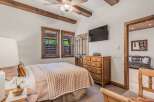 Experience rustic charm in this inviting bedroom, featuring exposed wooden beams and a cozy quilt-covered bed.