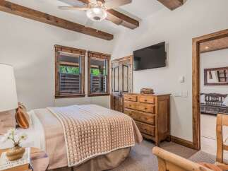 Experience rustic charm in this inviting bedroom, featuring exposed wooden beams and a cozy quilt-covered bed.