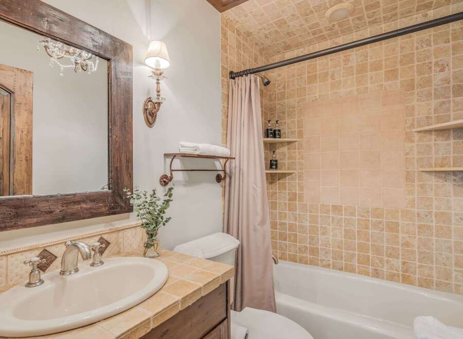This charming bathroom features a rustic wooden vanity with a cream-colored sink and elegant silver fixtures.