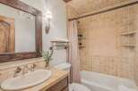 This charming bathroom features a rustic wooden vanity with a cream-colored sink and elegant silver fixtures.