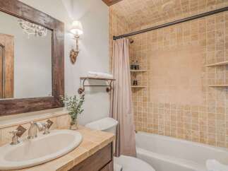 This charming bathroom features a rustic wooden vanity with a cream-colored sink and elegant silver fixtures.