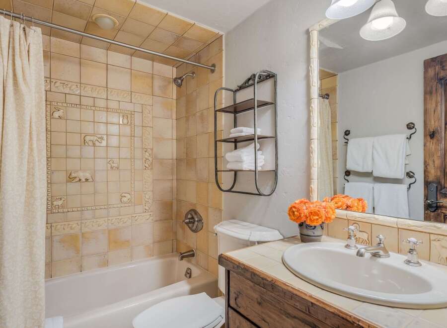 Charming bathroom featuring a bathtub with a decorative tile surround showcasing woodland creatures.